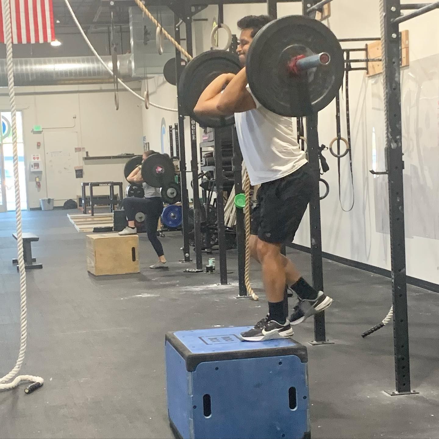 A man squatting with a barbell over his head in a gym