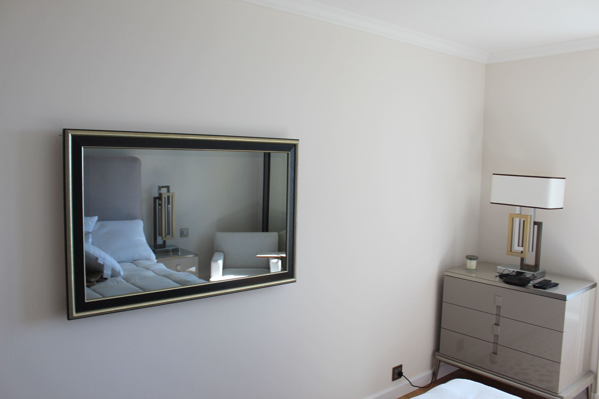 Une chambre avec un grand miroir sur le mur au-dessus du lit