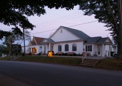 A large white house sits on the side of a road