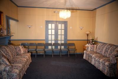 A living room with a couch , chairs and a chandelier.