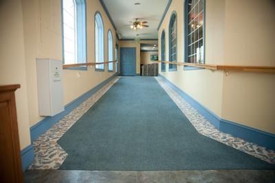 A long hallway with a blue carpet and a lot of windows.