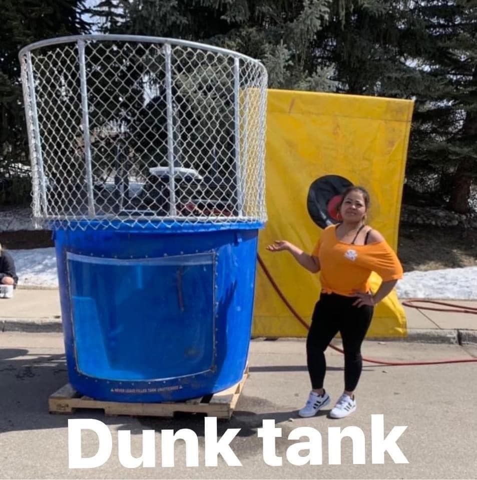 A woman stands in front of a large blue dunk tank
