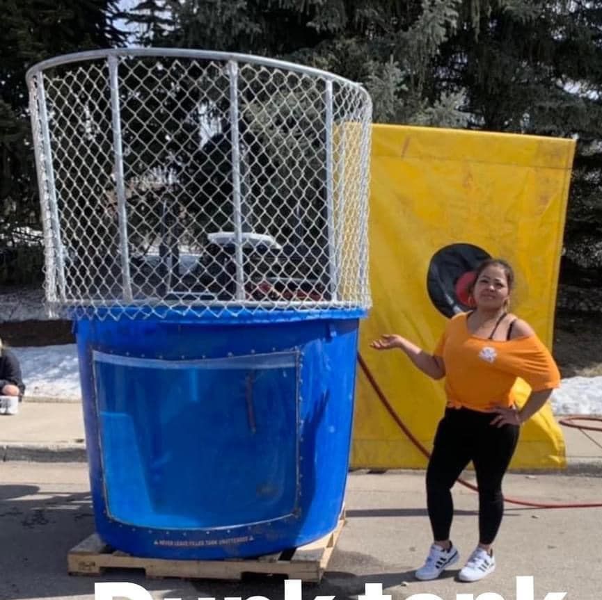 A woman stands in front of a large blue dunk tank