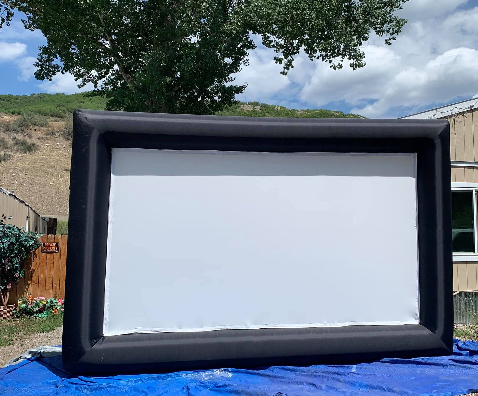 A large inflatable screen is sitting on top of a blue tarp.
