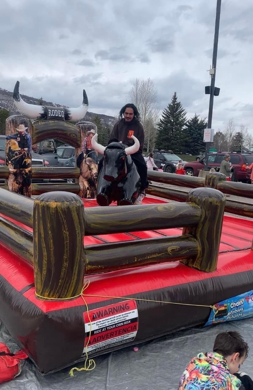 A man is riding a bull in an inflatable rodeo.