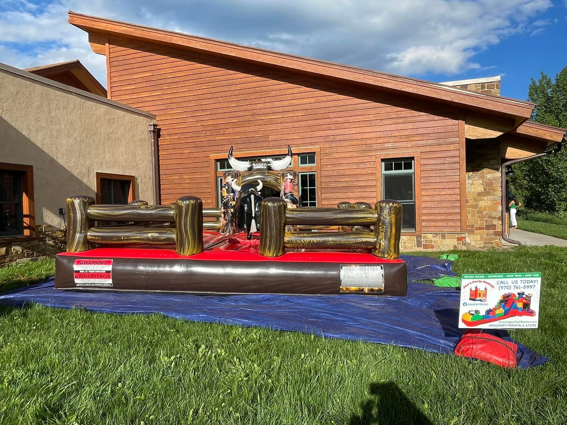 A bouncy house with a bull in it is sitting in front of a brick building.