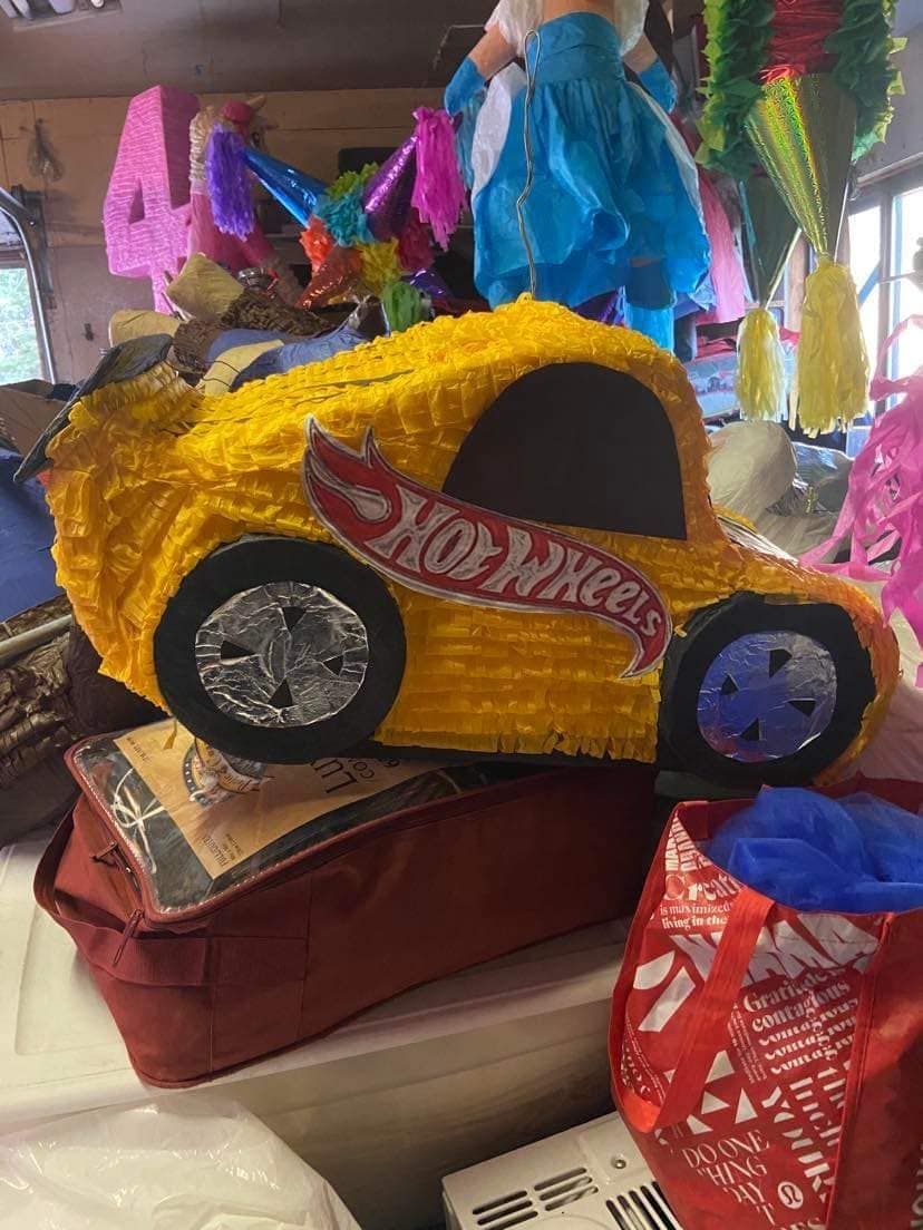 A yellow hot wheels piñata is sitting on top of a red bag.