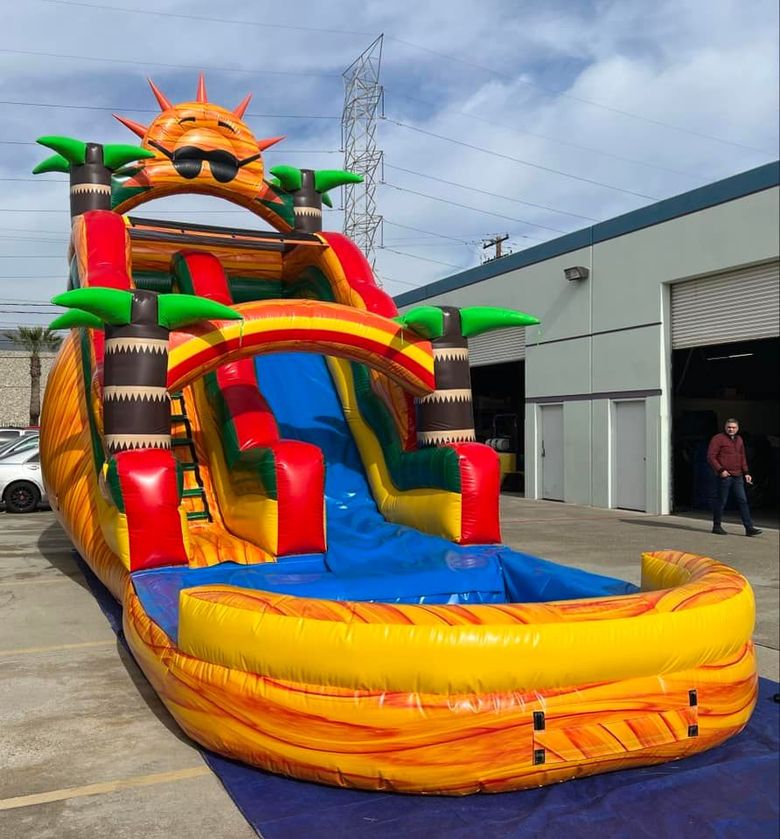 A colorful bouncy house is sitting on top of a blue tarp.