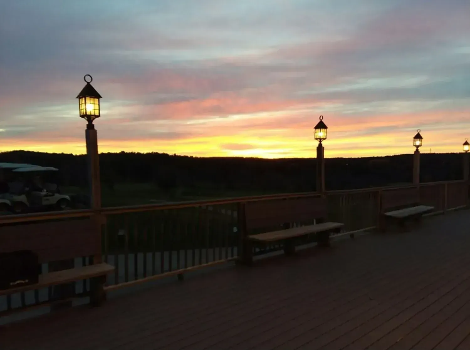 A wooden deck with a sunset in the background