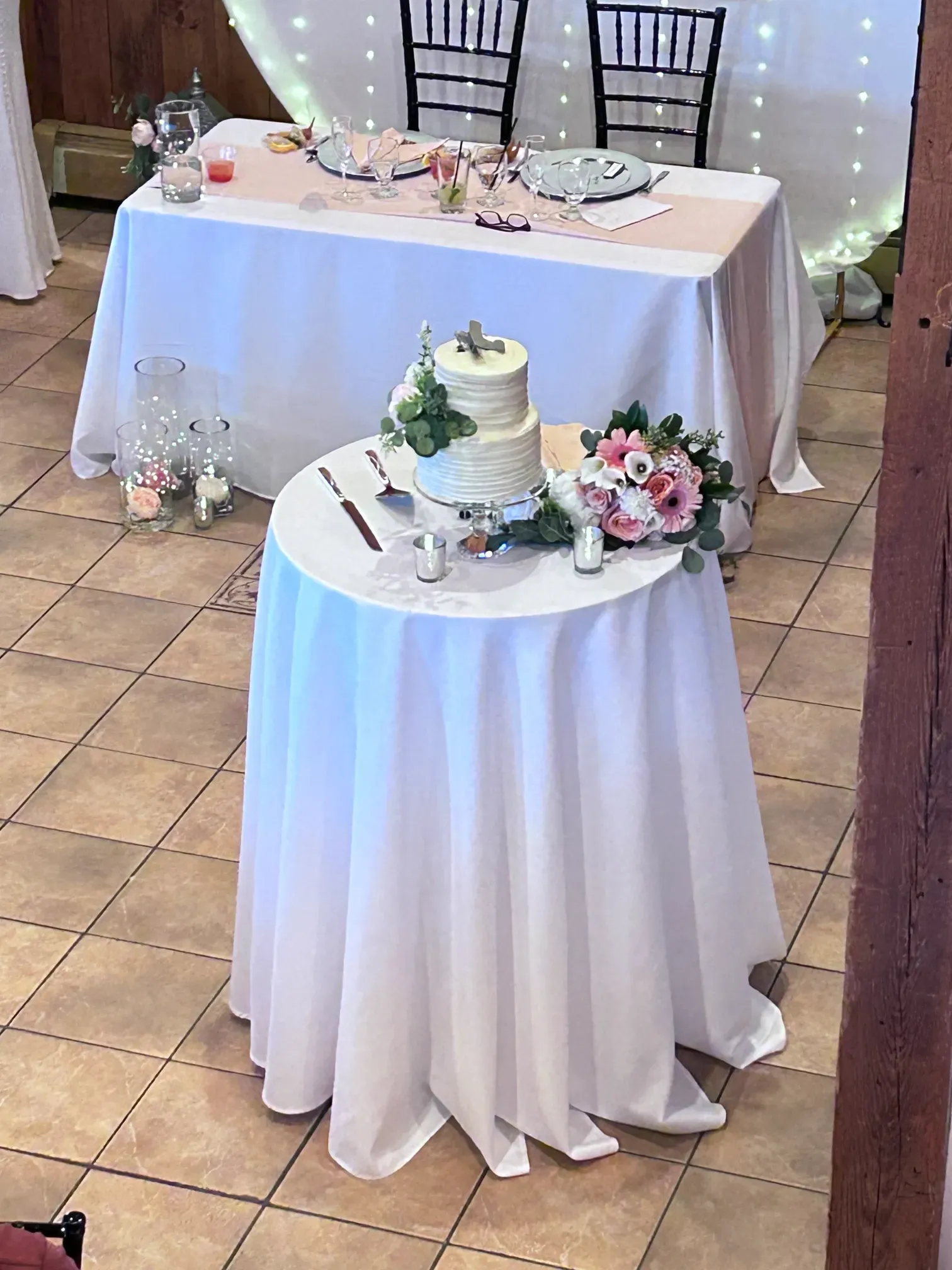 A wedding cake is on a table with a white table cloth.