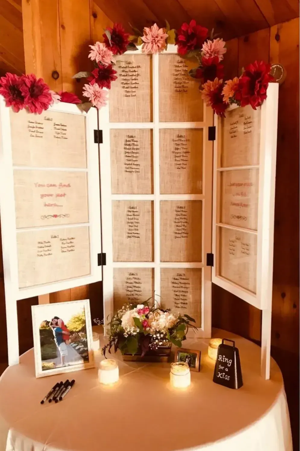 A table with a white table cloth and a white screen with flowers on it.
