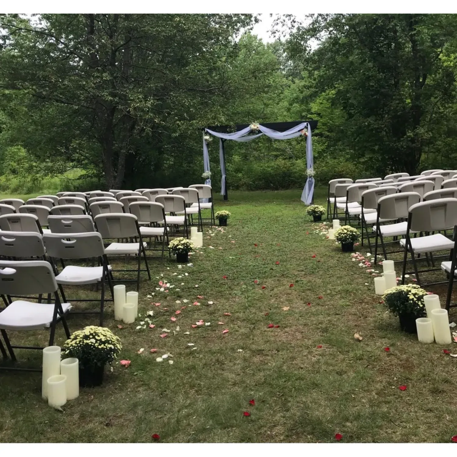 A row of folding chairs in a field with candles and flowers