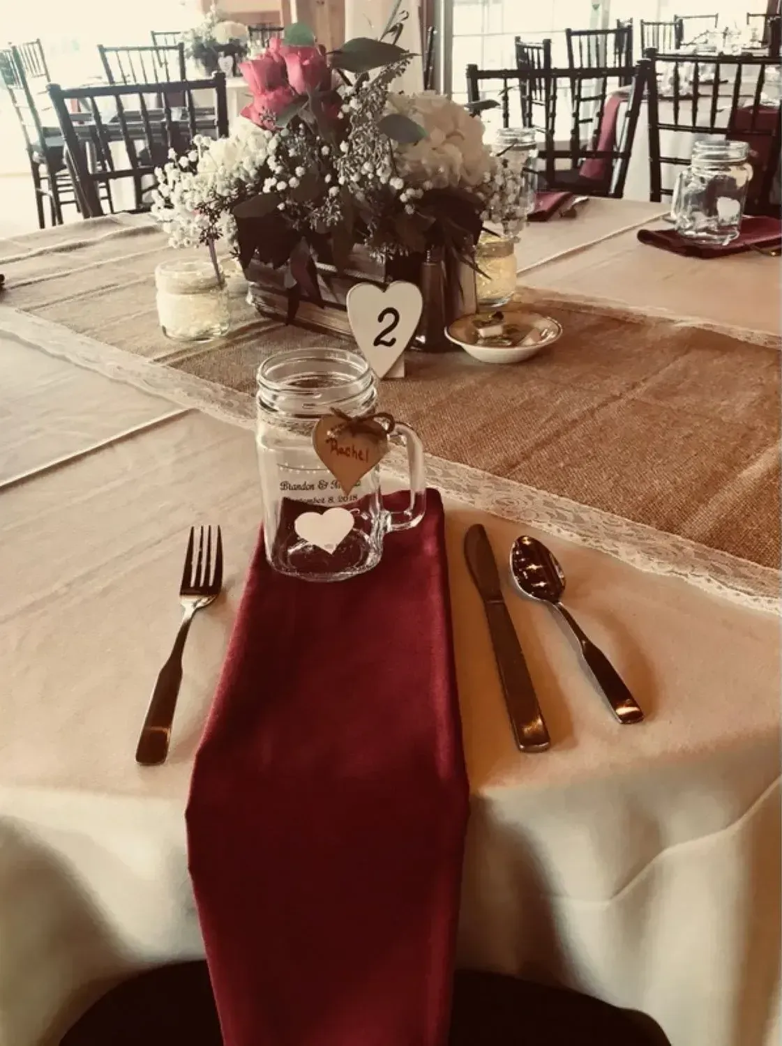 A table set for a wedding reception with a mason jar with a heart on it.