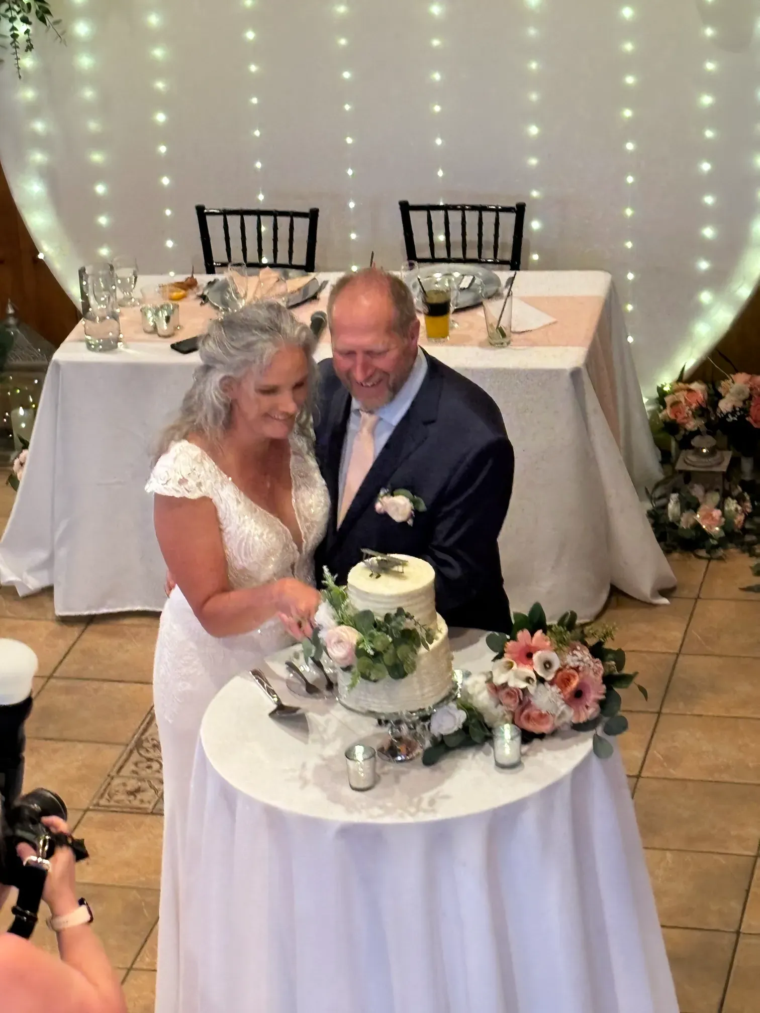 A bride and groom are cutting their wedding cake on a table.