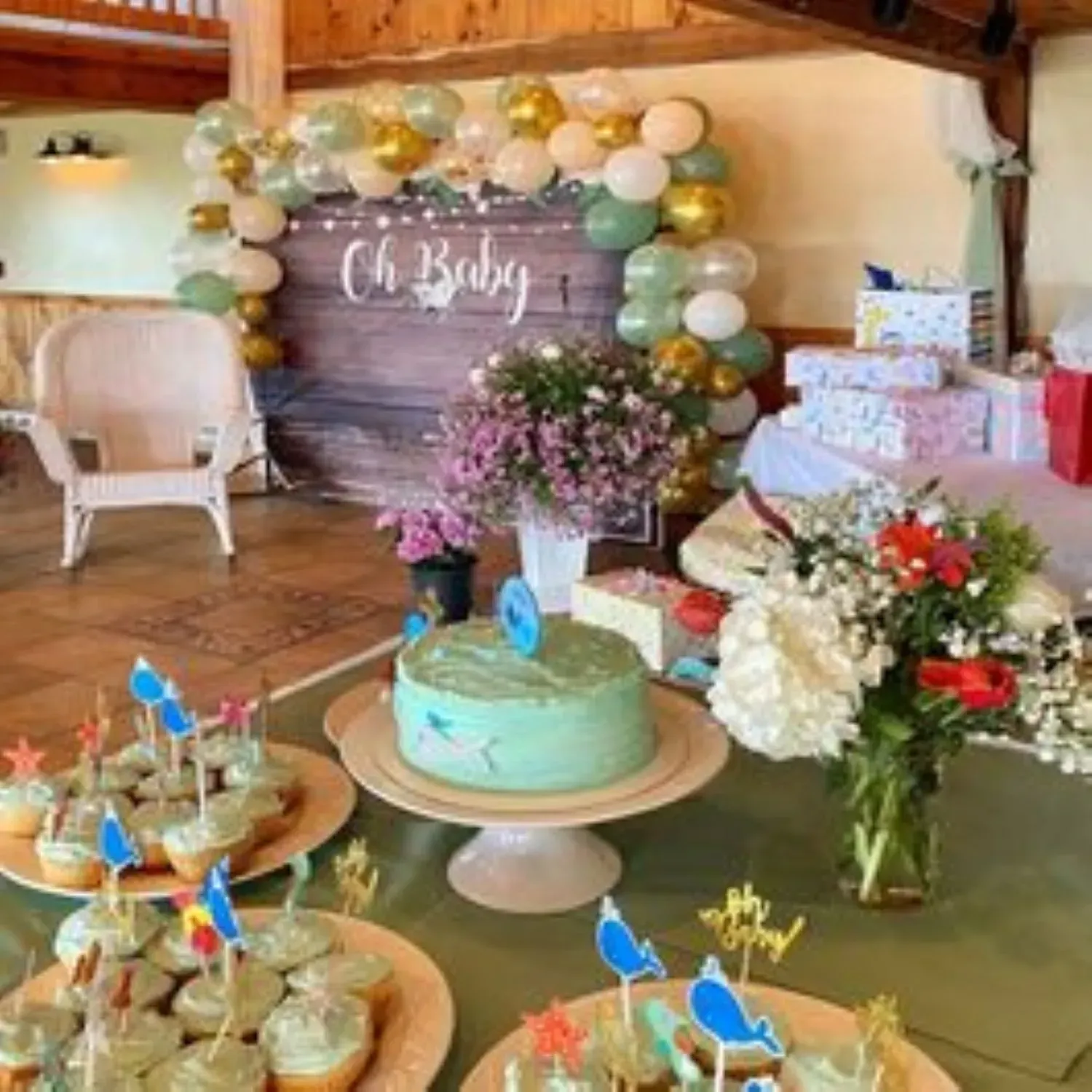 A table with cupcakes and a cake with a sign that says oh baby