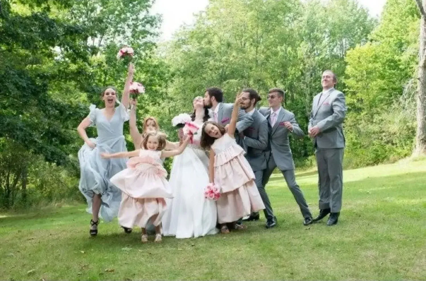A bride and groom are posing for a picture with their wedding party.
