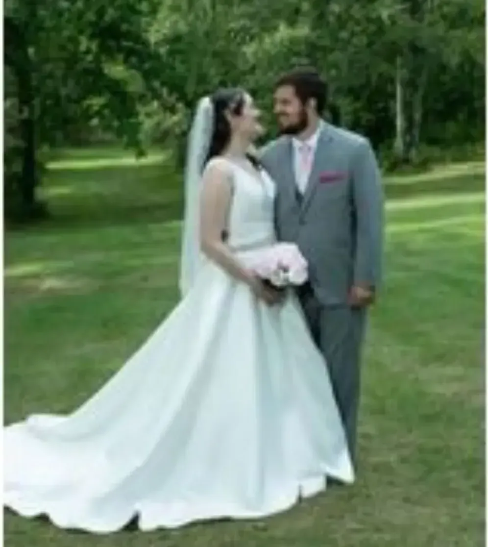 A bride and groom are posing for a picture in a park.