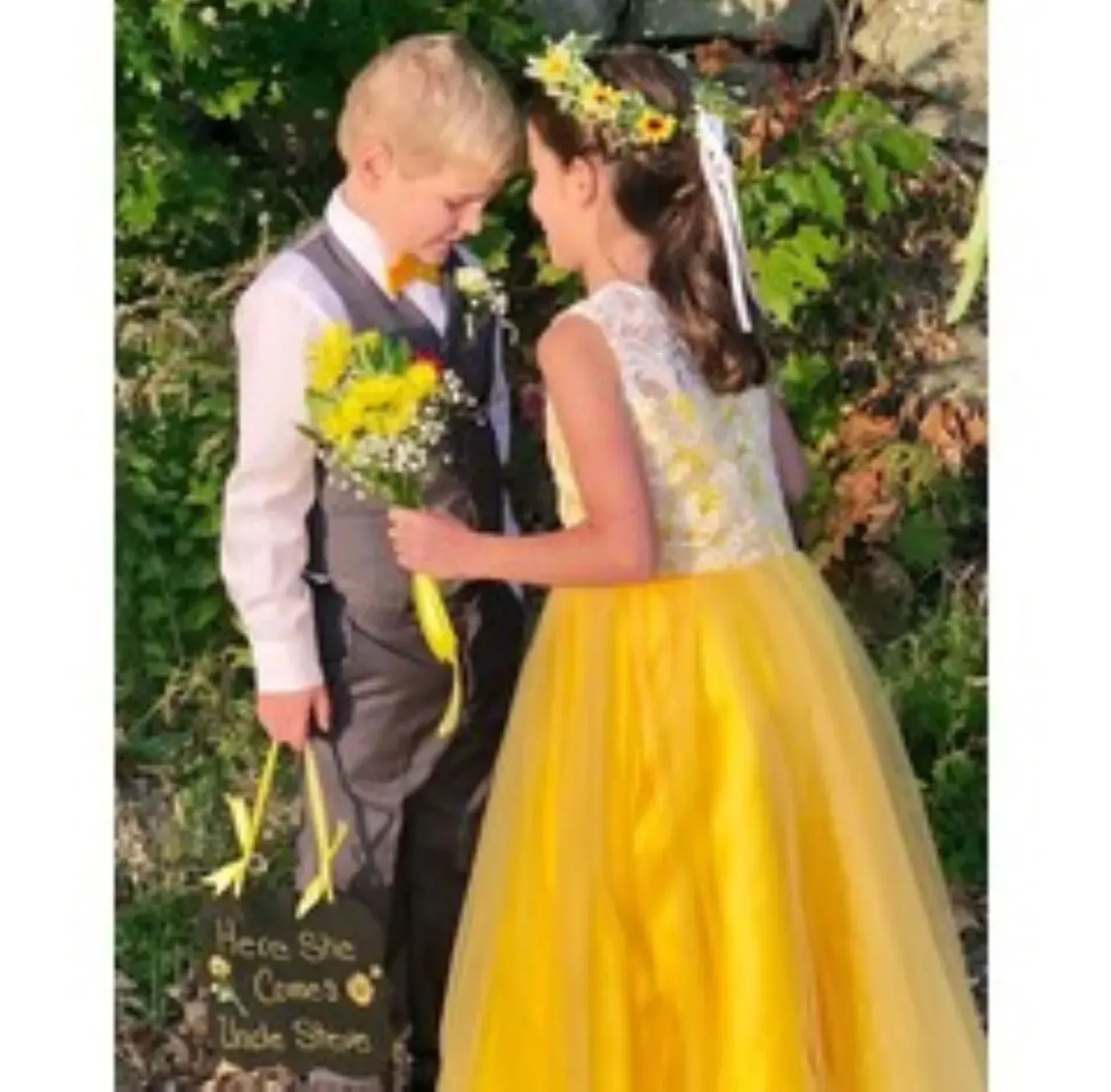A boy and a girl are standing next to each other and the girl is wearing a yellow dress