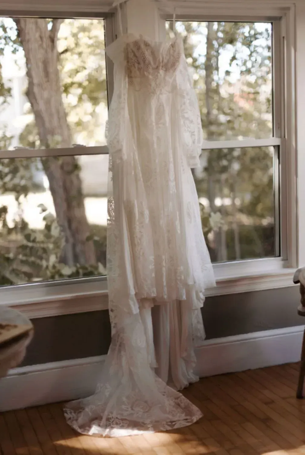 A wedding dress is hanging on a window sill in a room.