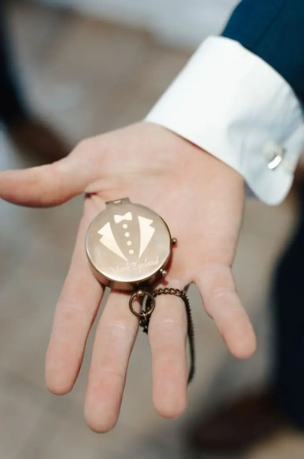 A man in a tuxedo holds a pocket watch in his hand