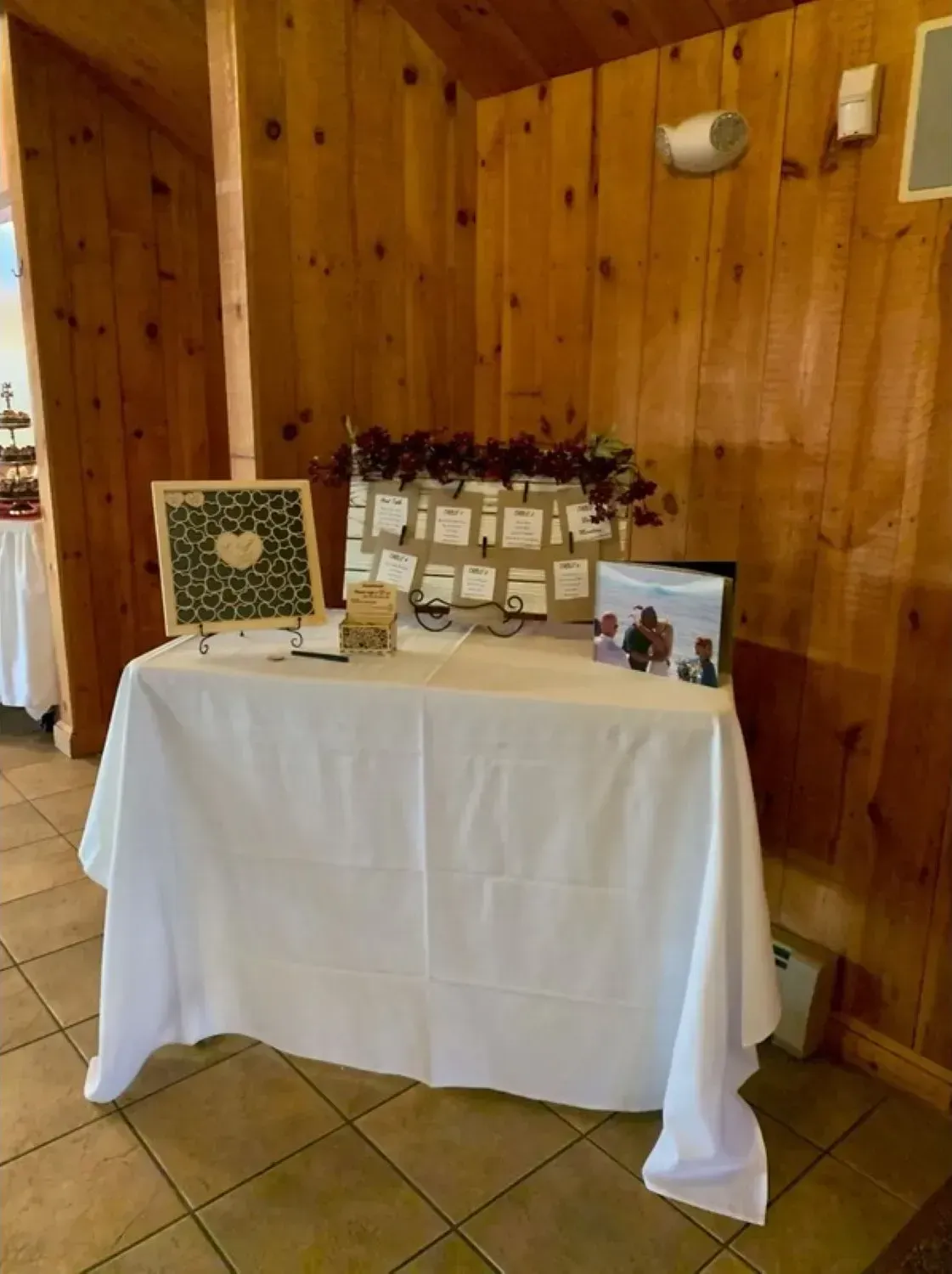 A table with a white tablecloth is sitting in a room with wooden walls.