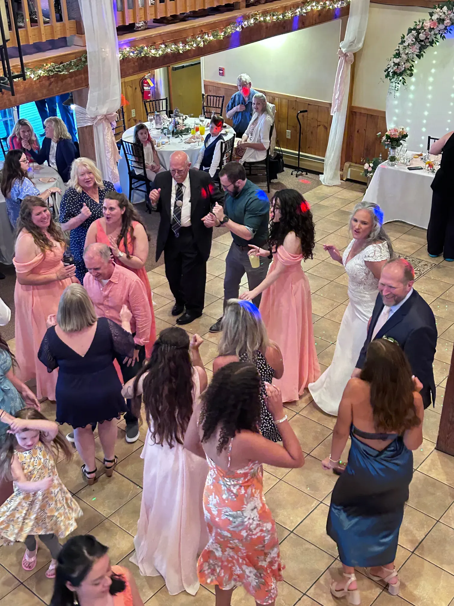 A group of people are dancing in a room at a wedding reception.