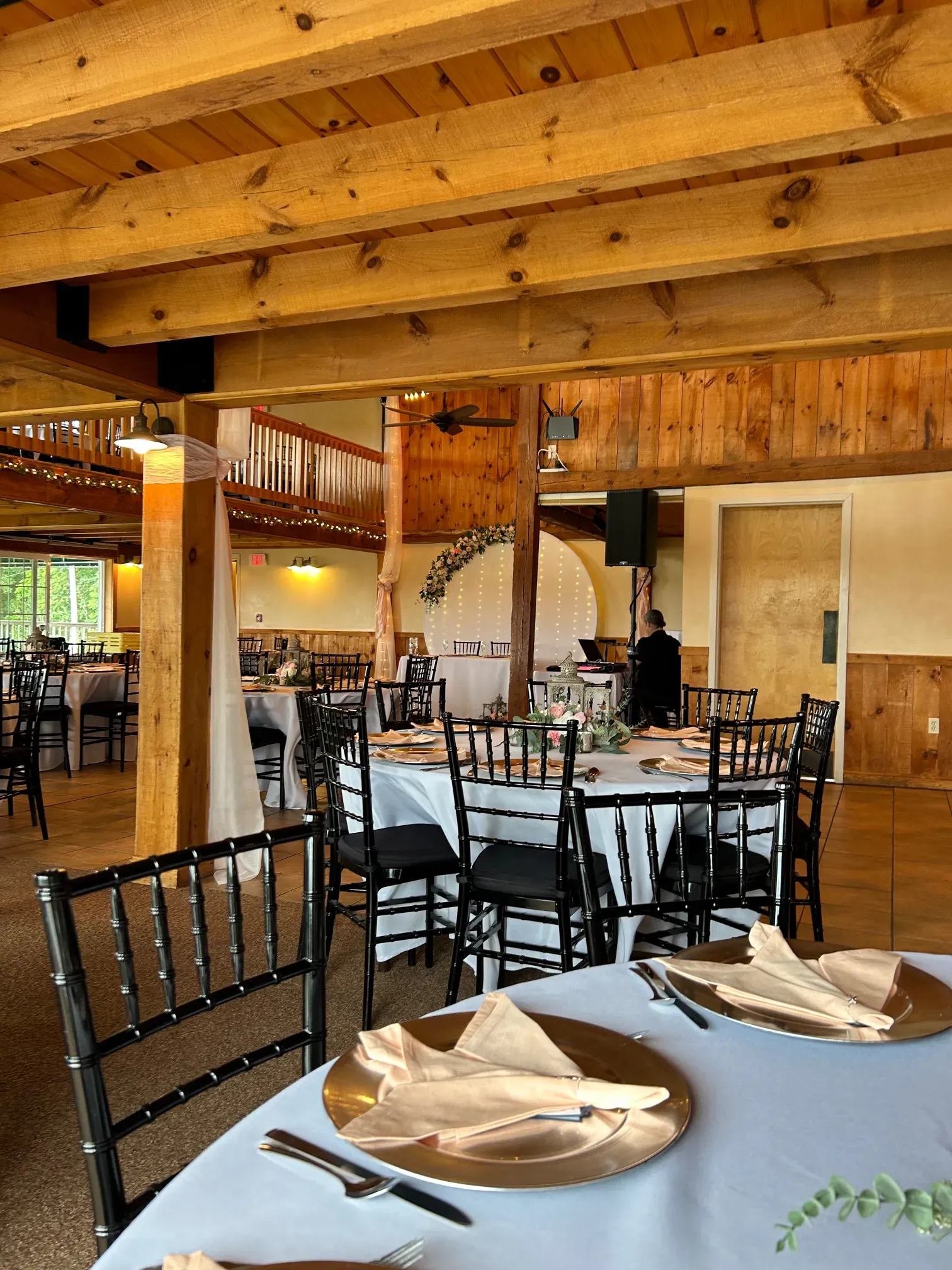 A large room with tables and chairs set up for a wedding reception.