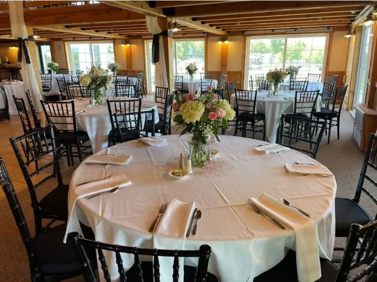 A large room with tables and chairs set up for a wedding reception.
