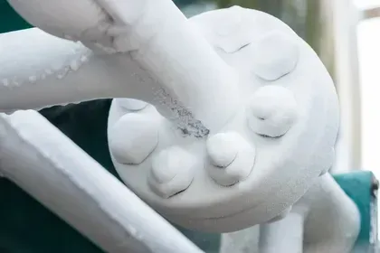 A white, round sculpture resembling a spider's body with leg attachments.