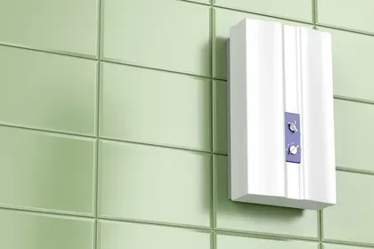 White water heater on a green tiled wall.