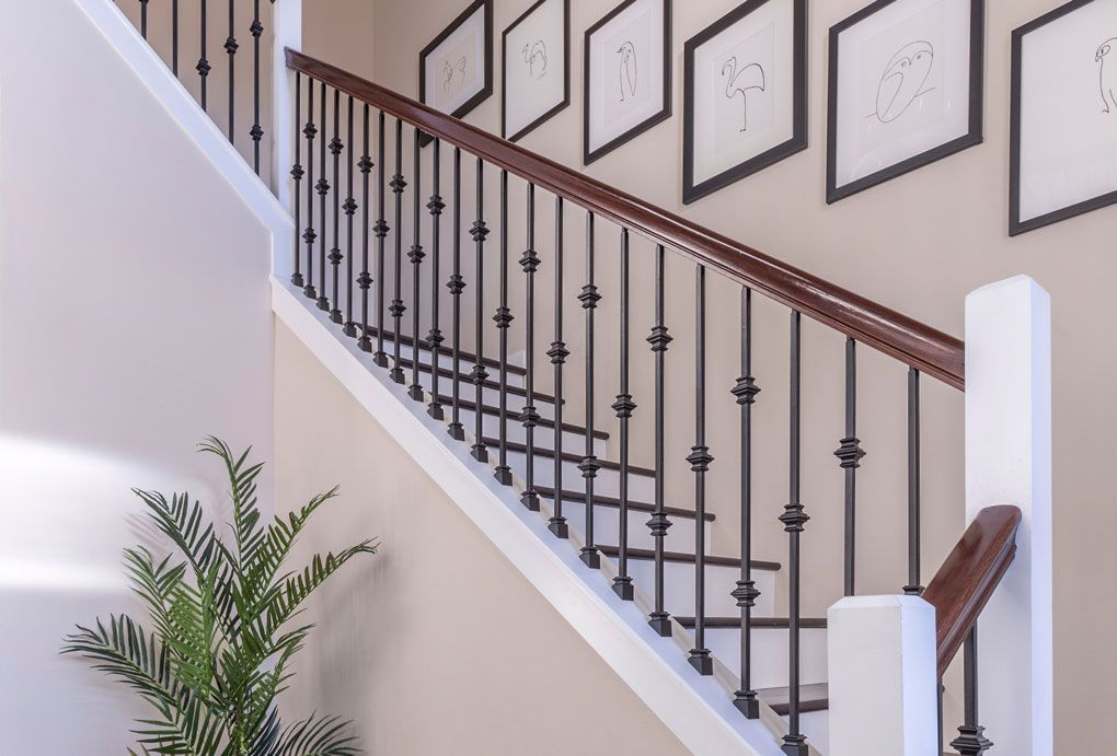 Contemporary staircase showcasing intricate black metal railings and newly painted trims along the casing.