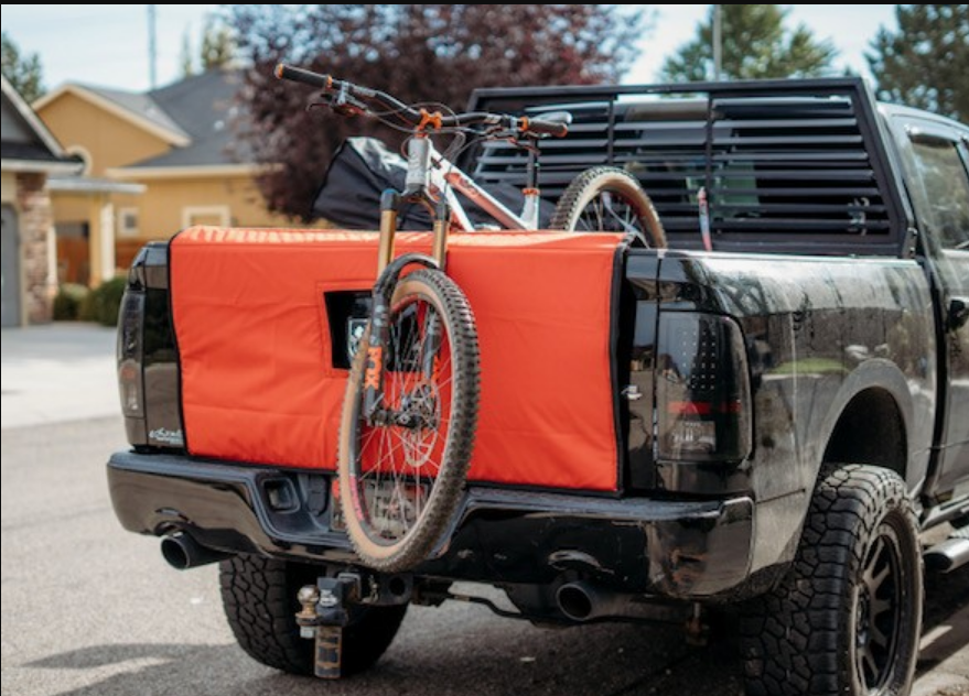 Red mountain bike with person standing, arms outstretched, on hilltop overlooking city.