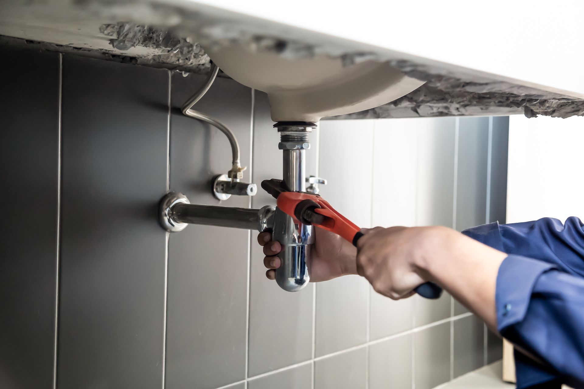 Plumbing fix in action wrench-tightening sink P-trap to prevent leaks