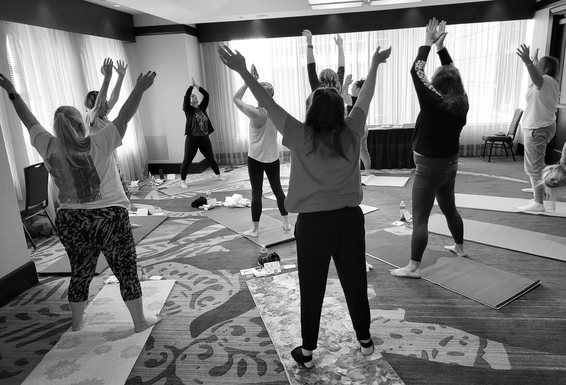 Cassandra Storm in tree pose on a rock and Liz Tattersall holding hands in prayer standing in a lily pond