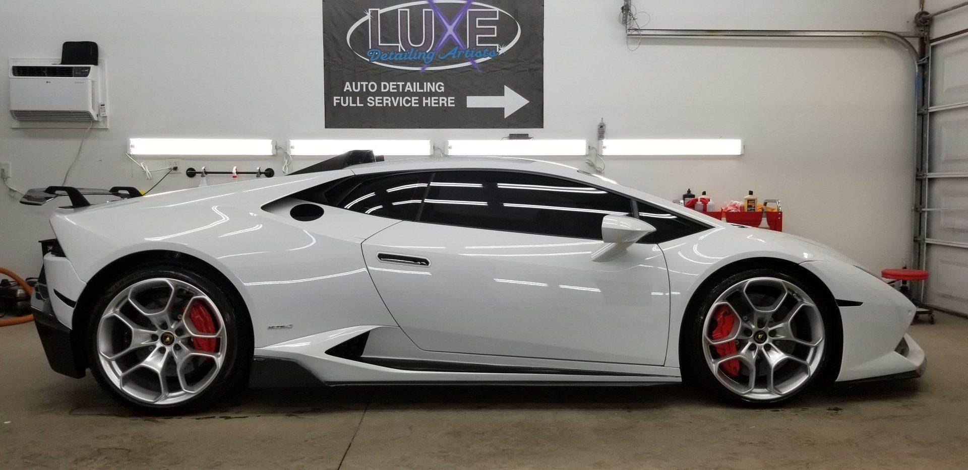 White Lamborghini in a garage with red brake calipers.