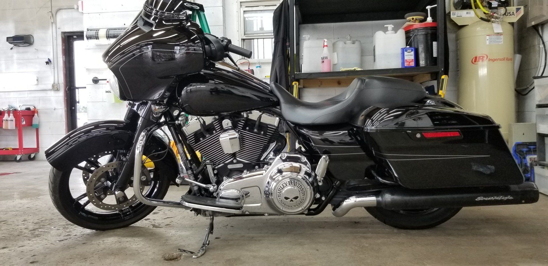 Black Harley-Davidson motorcycle parked indoors, chrome engine, black fairing, saddlebags, and exhaust.