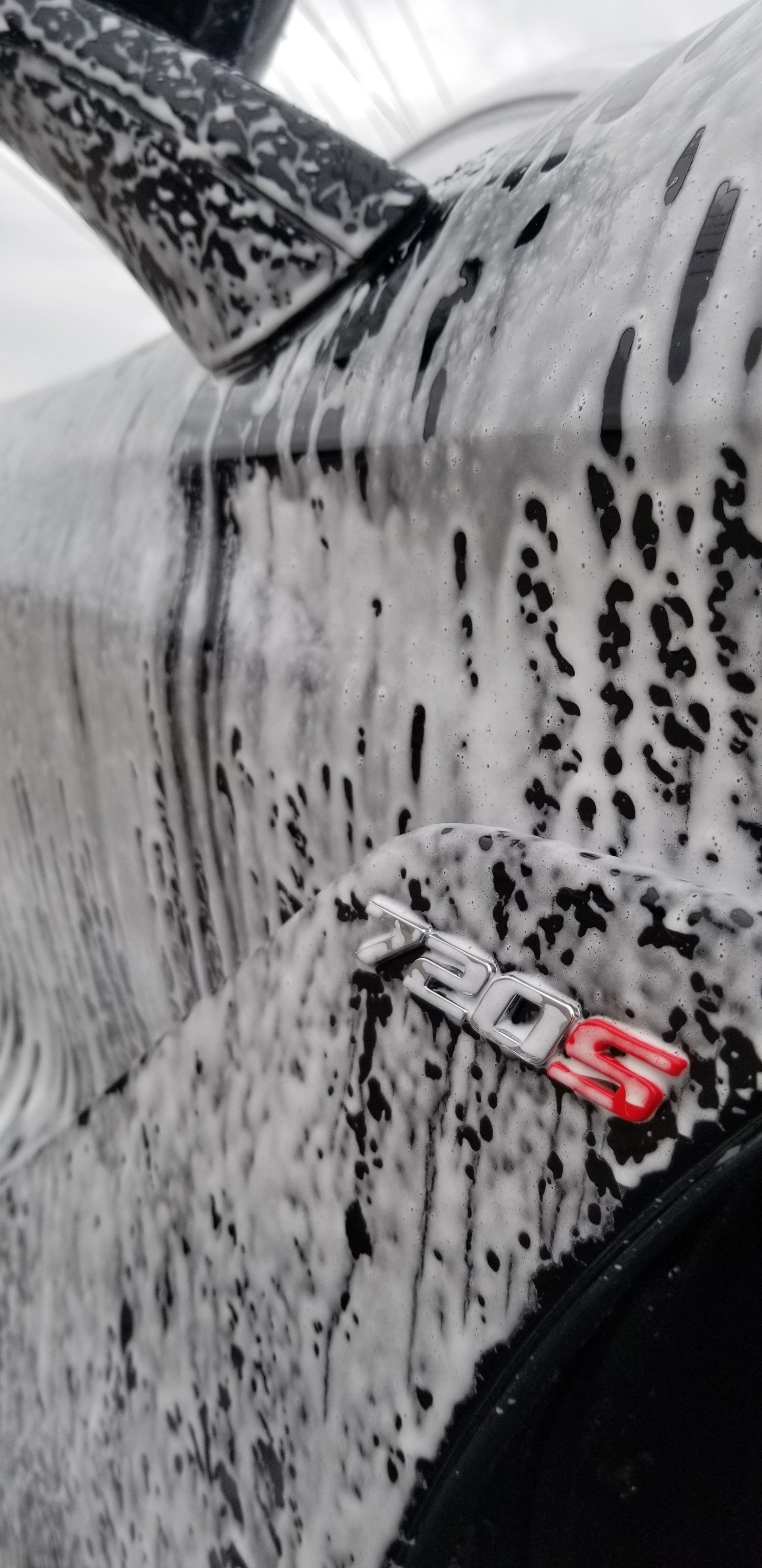 Car door being washed with foam, showcasing a red 