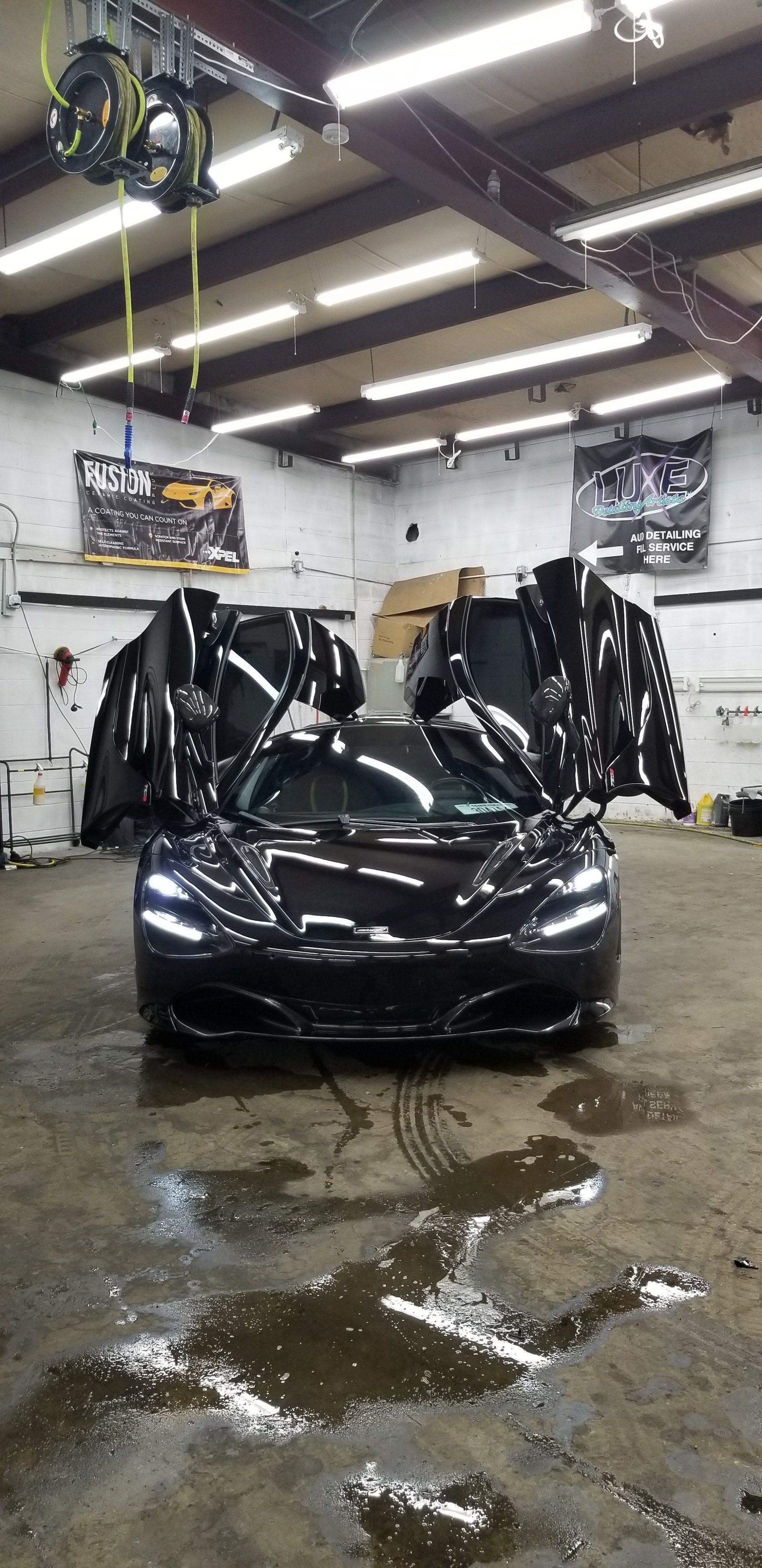 Black sports car with doors open in a garage.