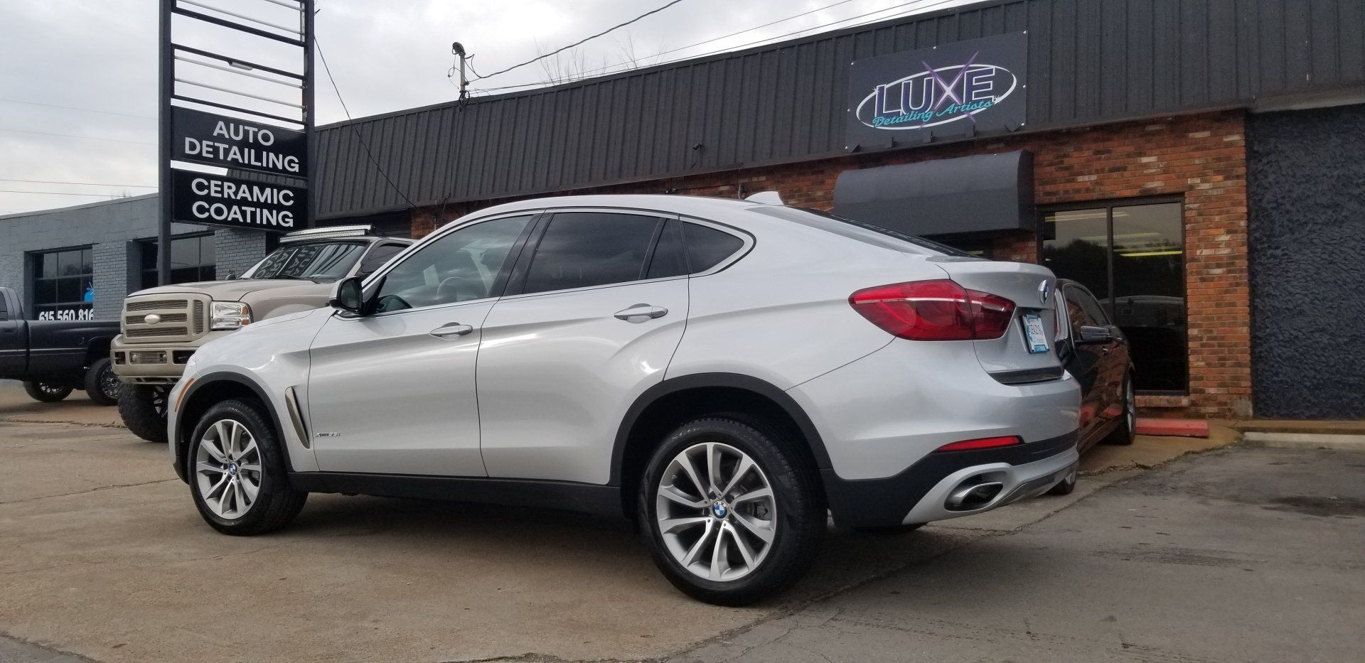Silver BMW SUV parked in front of a business.