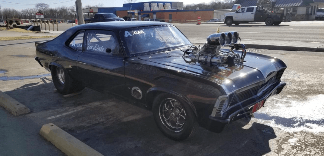 Black muscle car with a large engine parked outside.