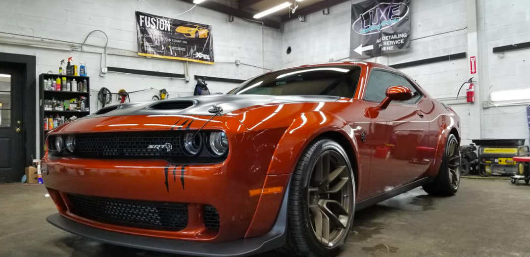 Orange Dodge Challenger in an auto shop.