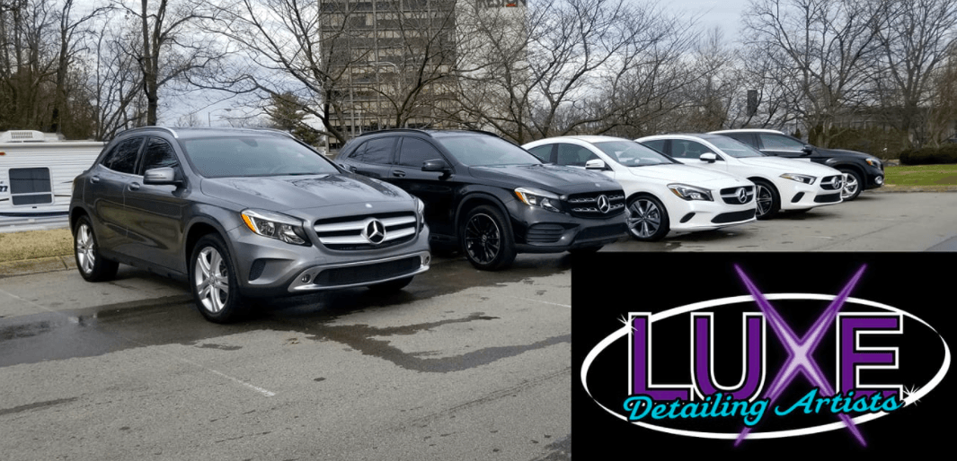Line of luxury vehicles parked outdoors with a detailing company logo.