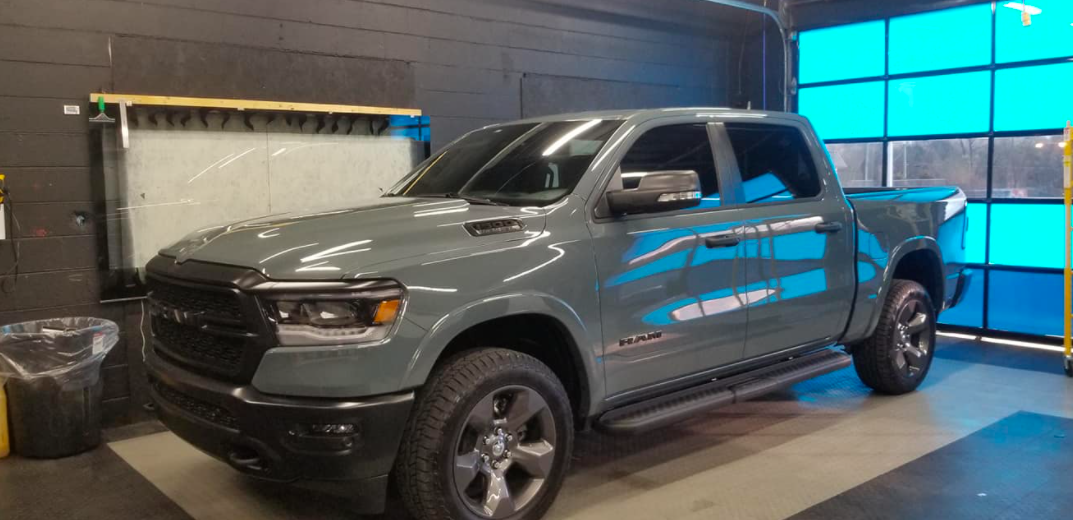 Gray Ram pickup truck parked inside a garage with a blue door.