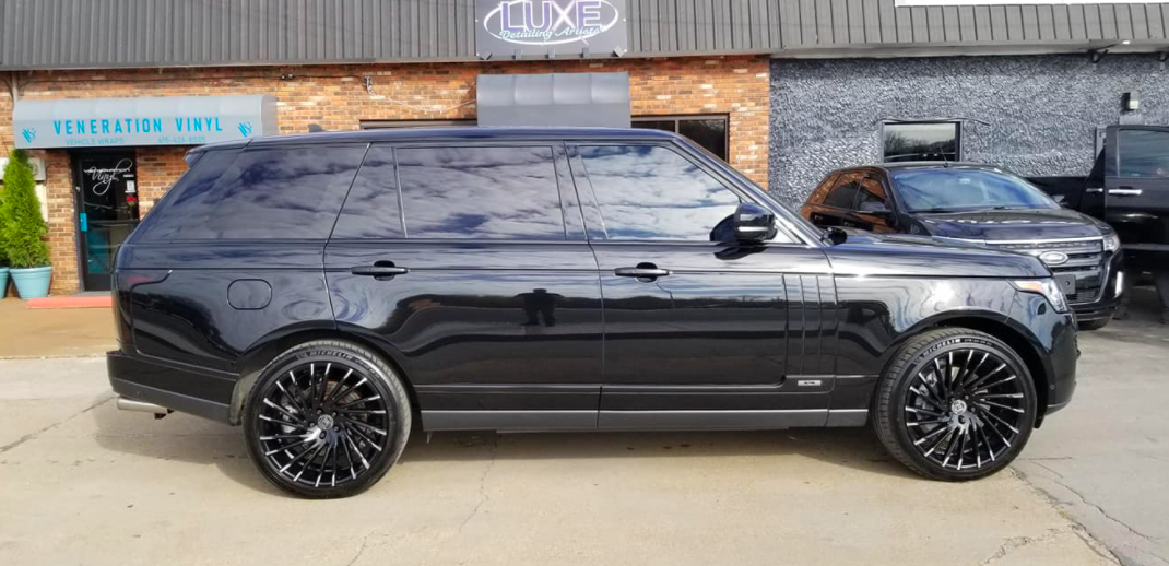 Black Range Rover SUV with tinted windows parked outside a building.