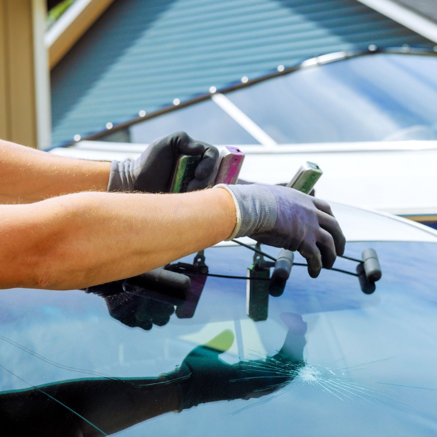 Arms in protective gloves repair a car windshield with a crack using specialized tools Arms in protective gloves repair a car windshield with a crack using specialized tools