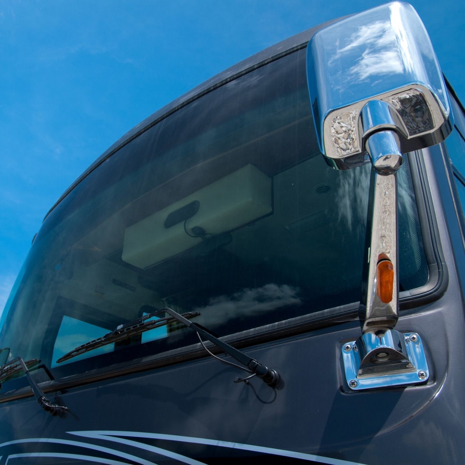 Close-up of a shiny chrome side mirror and windshield wipers of RV Close-up of a shiny chrome side mirror and windshield wipers of RV