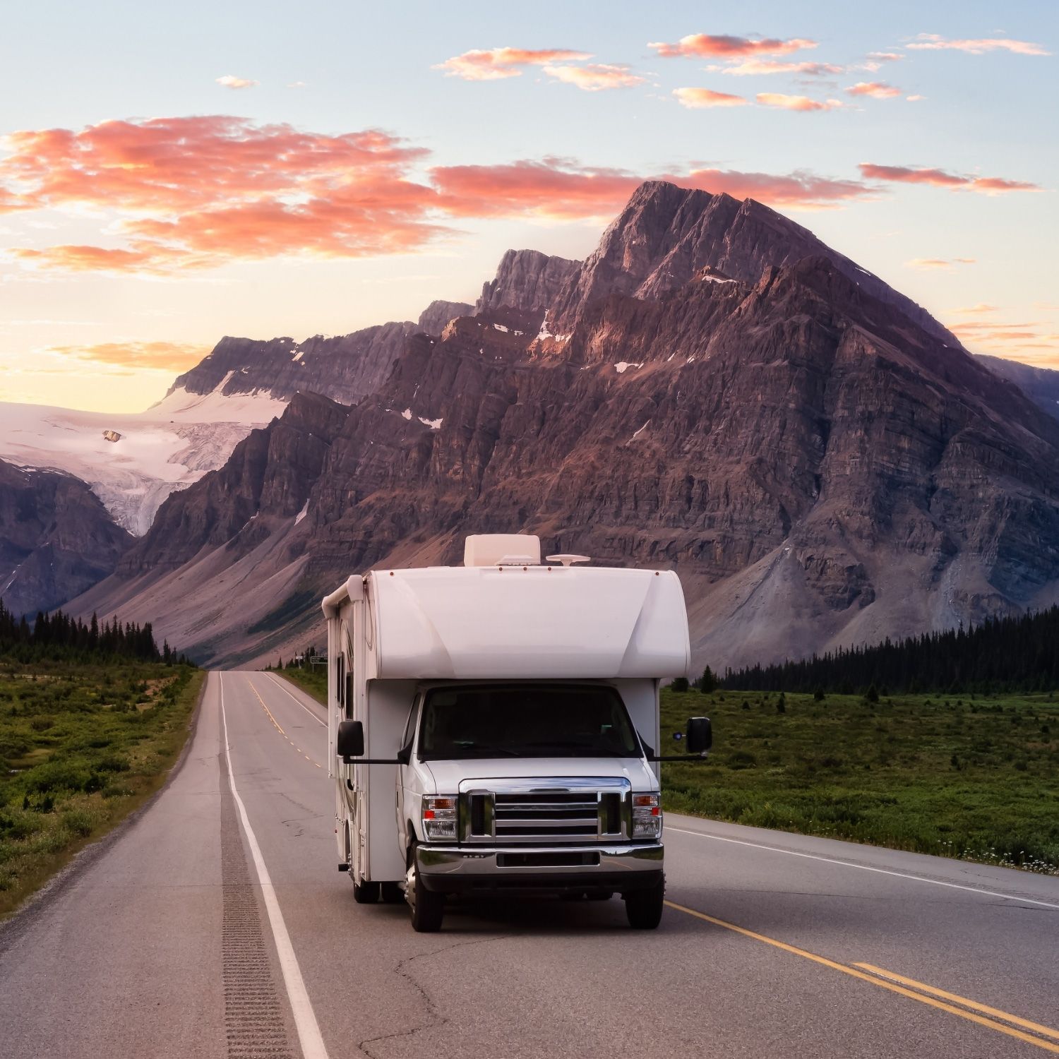 A white RV drives on a scenic road with a majestic mountain backdrop at sunset A white RV drives on a scenic road with a majestic mountain backdrop at sunset