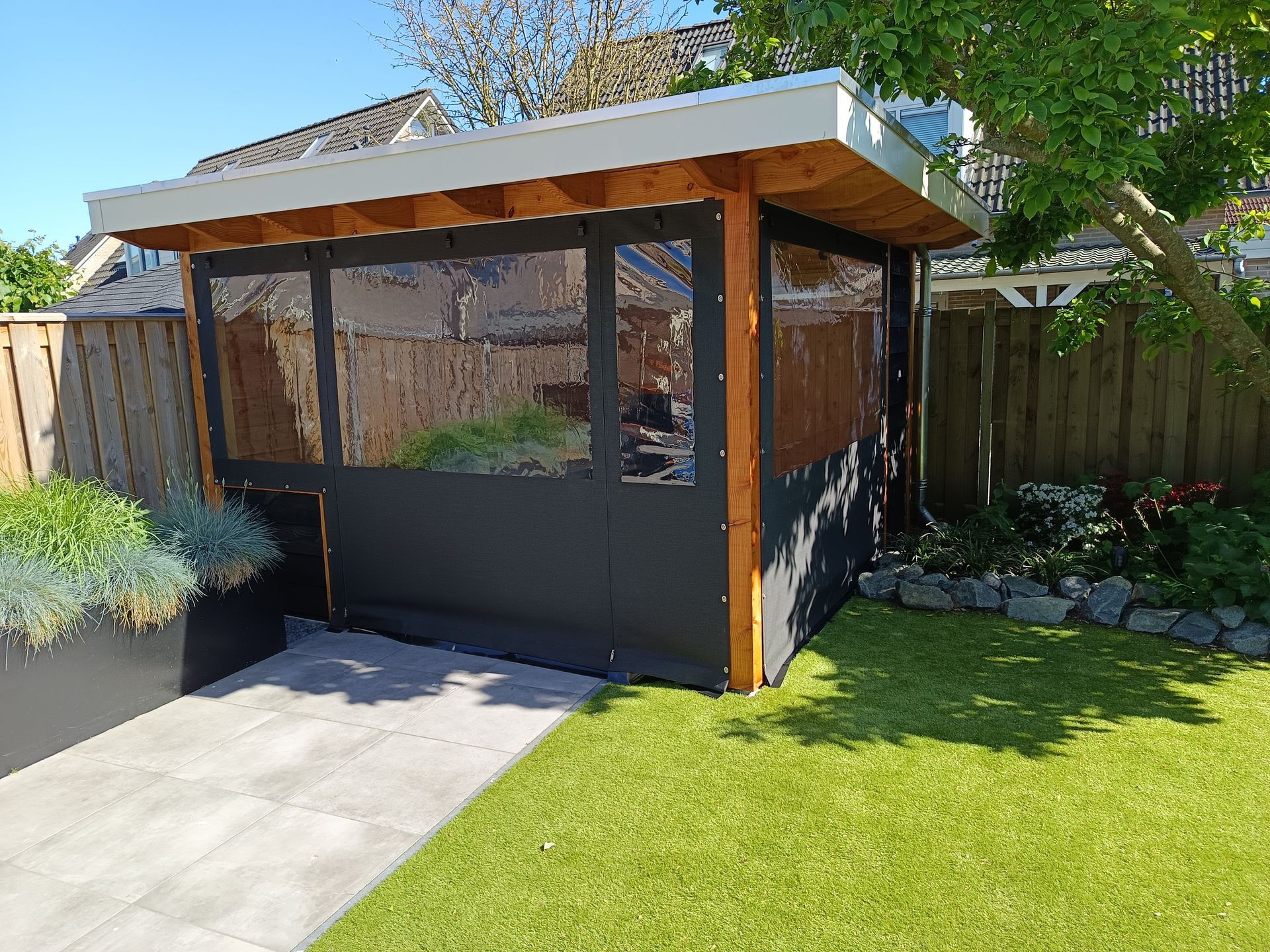 Een klein schuurtje in een achtertuin met een hek op de achtergrond.