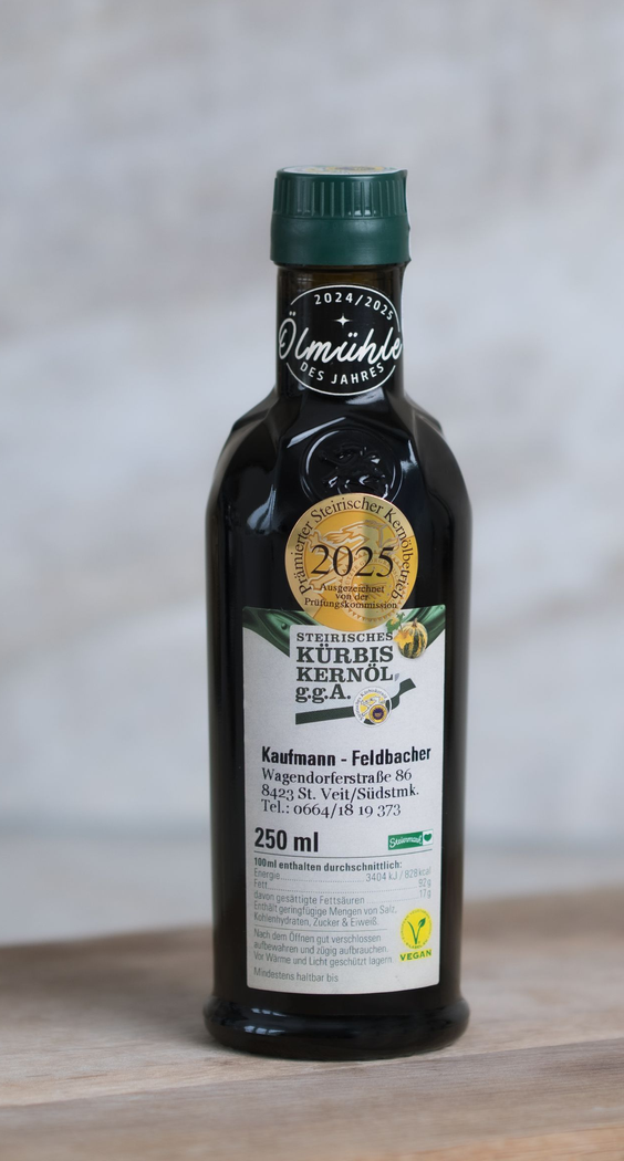 Kürbiskeröl mit grünem Verschluss und weißem Etikett auf einer Holzoberfläche.