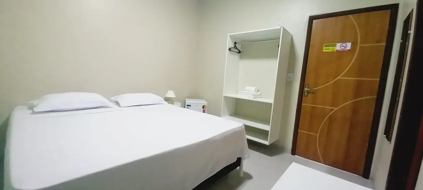 Um quarto com uma cama, armário e porta.
